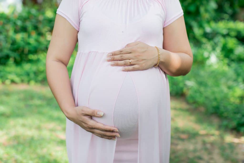 Imagem mostrando uma mulher de gestação avançada, acariciando a barriga