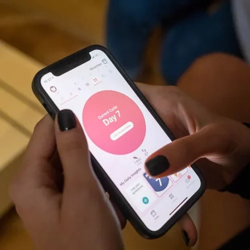 mulher com celular e app de ciclo menstrual na tela