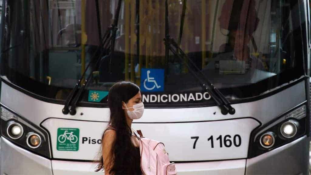 Moça atravessando rua em frente a ônibus