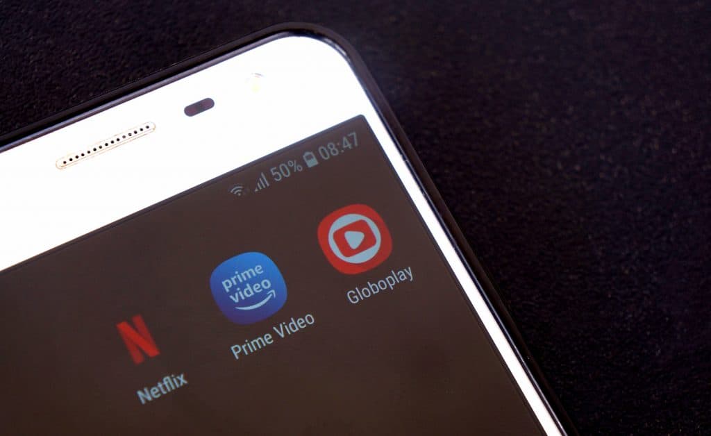 Tela de smartphone com imagens de logo dos apps de Netflix, Prime Video e Globoplay