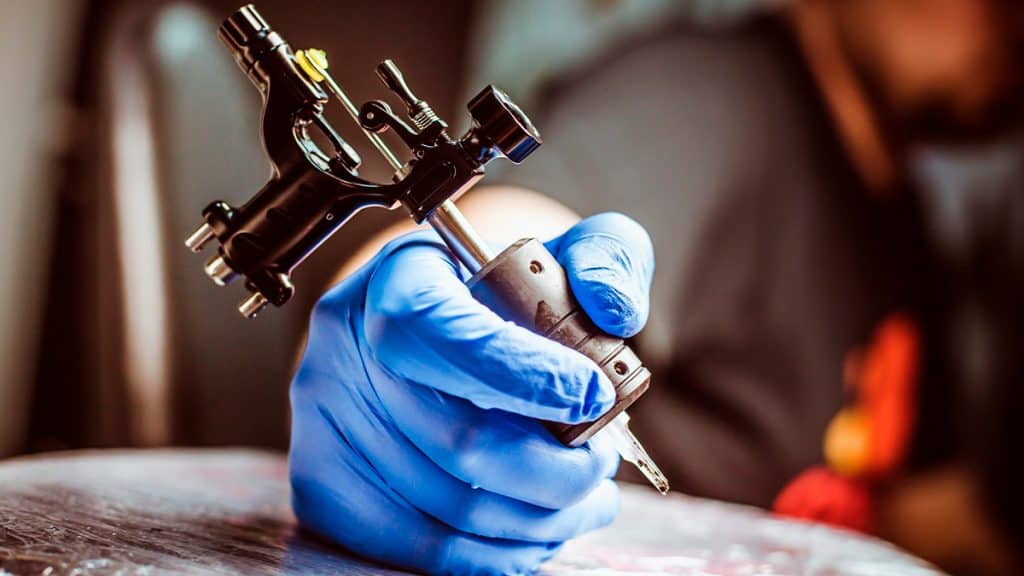 Pessoa segurando máquina de tatuar