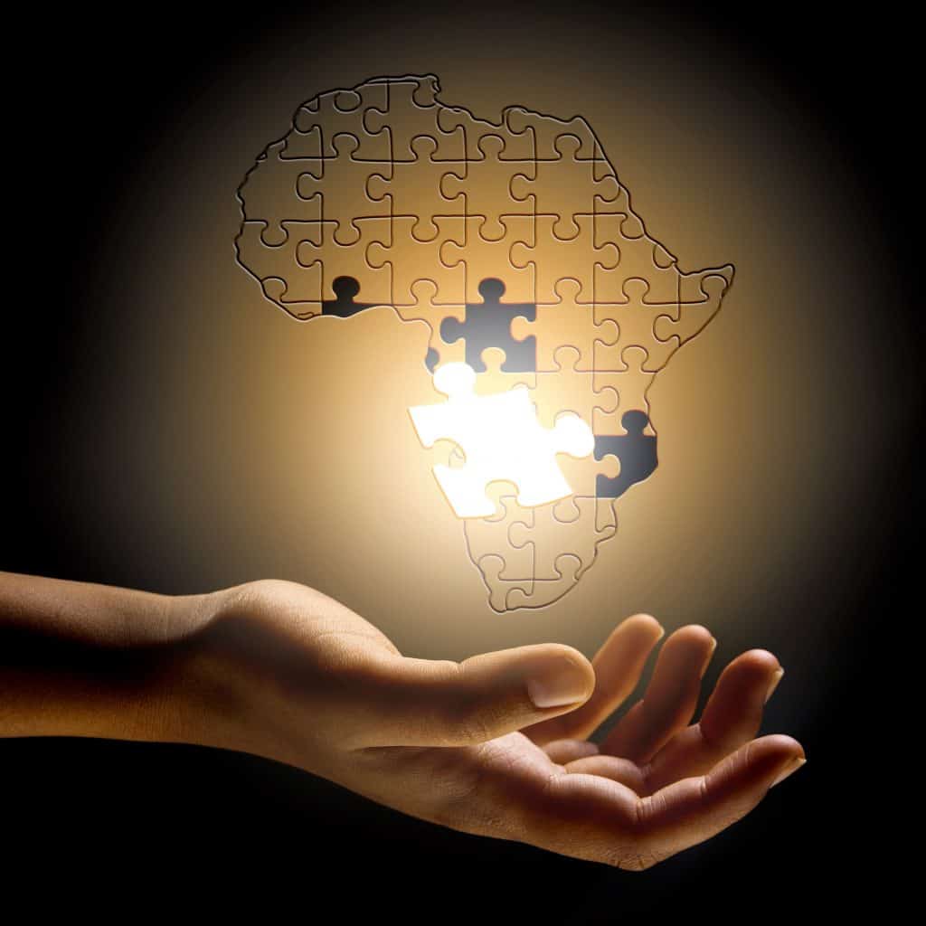 Mapa da África em formato de quebra-cabeça com uma mão humana embaixo dele