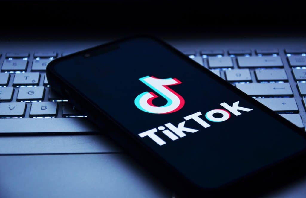 Logo do TikTok em um smartphone que está em cima de um notebook