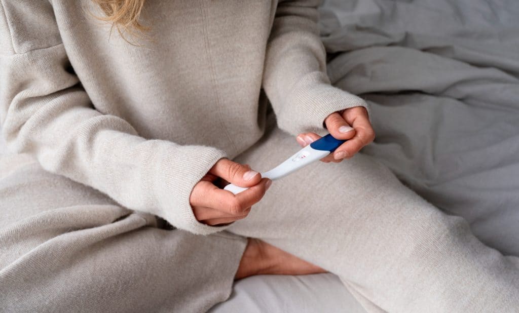 mulher com roupa de frio segurando teste de gravidez