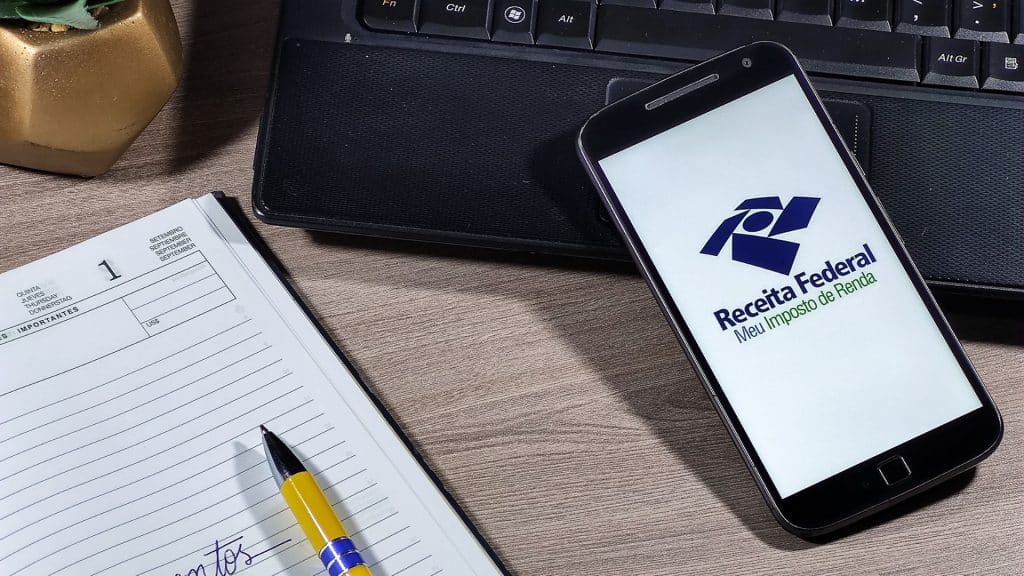 Receita Federal - Meu imposto de Renda (Brazilian Federal Revenue Department) logo on smartphone screen on office desk. Income tax declaration in Brazil