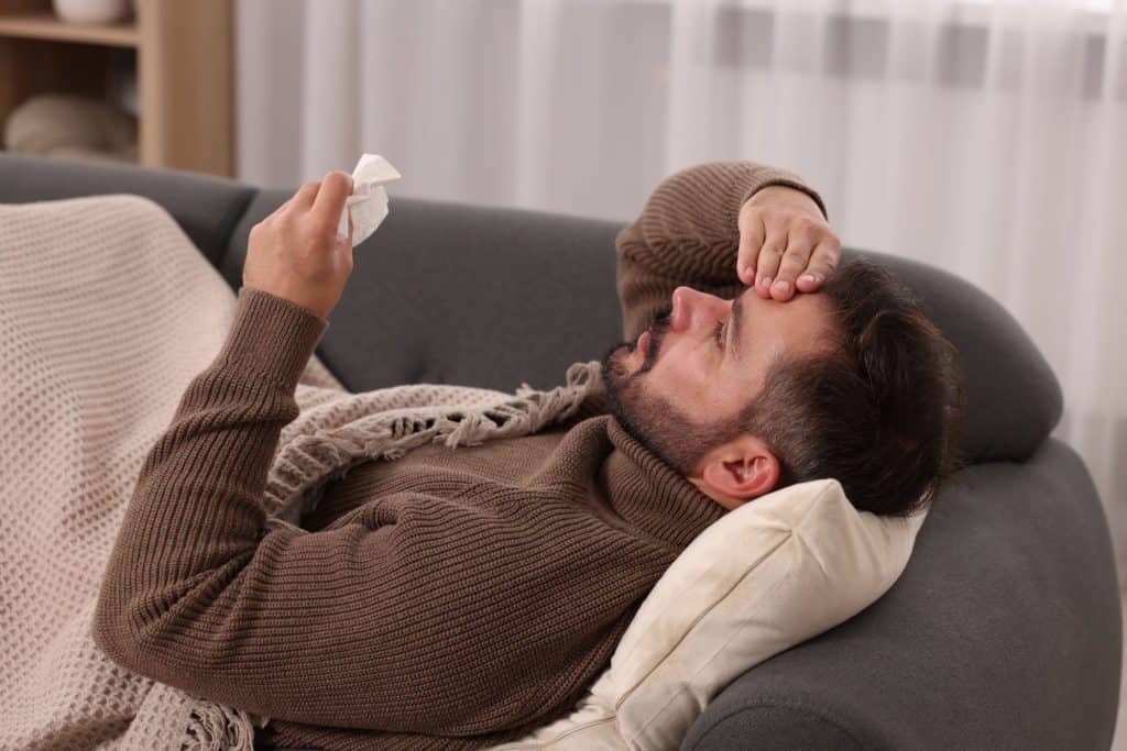 homem deitado no sofá com sintomas de gripe