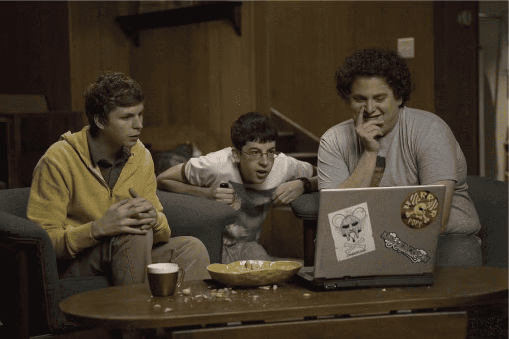 imagem mostra três adolescentes sentados no sofá enquanto mexem no pc