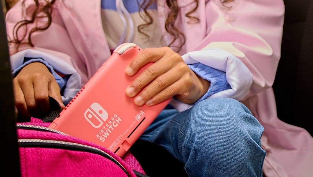Console Nintendo Switch Lite na cor coral sendo colocado em uma bolsa