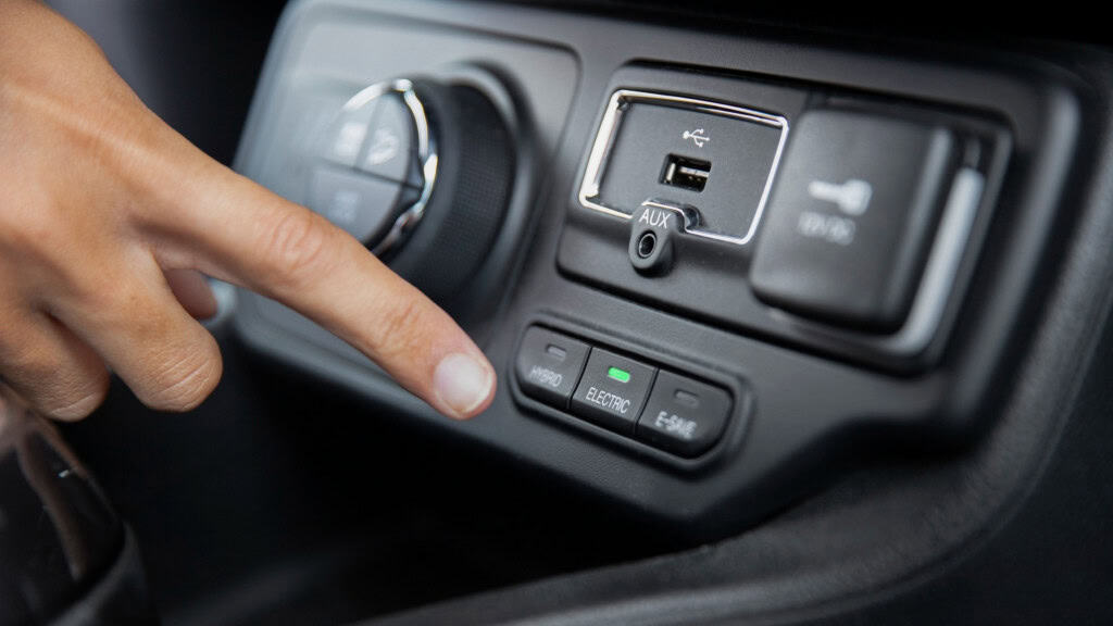 painel de veículo com porta usb visível e motorista ameaçando acionar um botão