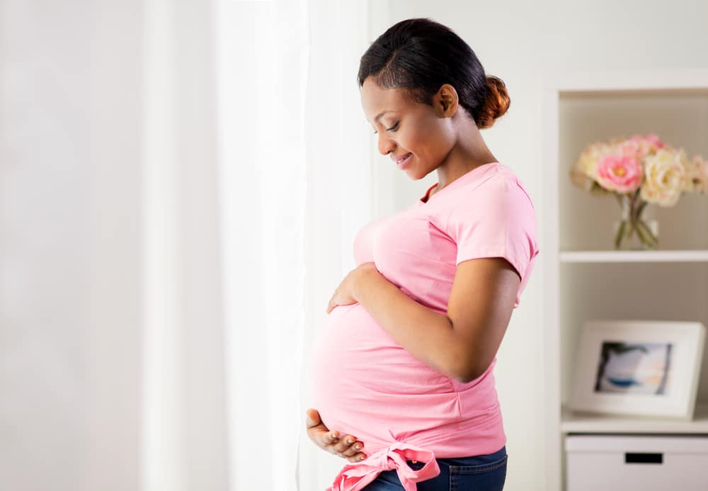 Mulher admirando sua barriga de grávida enquanto a acaricia com as mãos