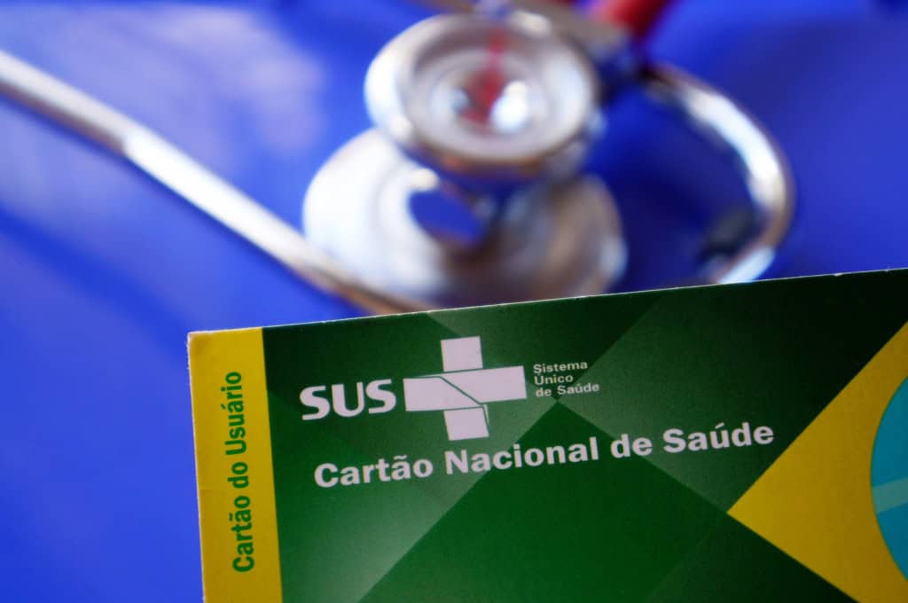 Carteirinha do SUS com um estetoscópio ao fundo