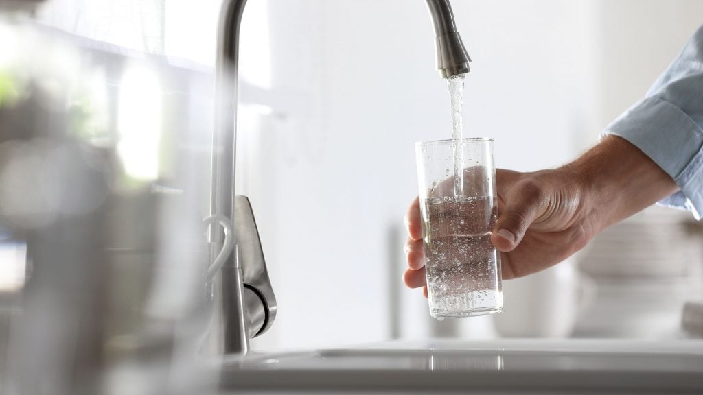 Homem servindo água em um copo na cozinha, close-up