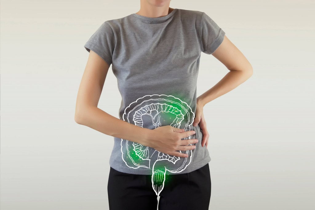 Mulher com a mão em cima do corpo onde fica o intestino