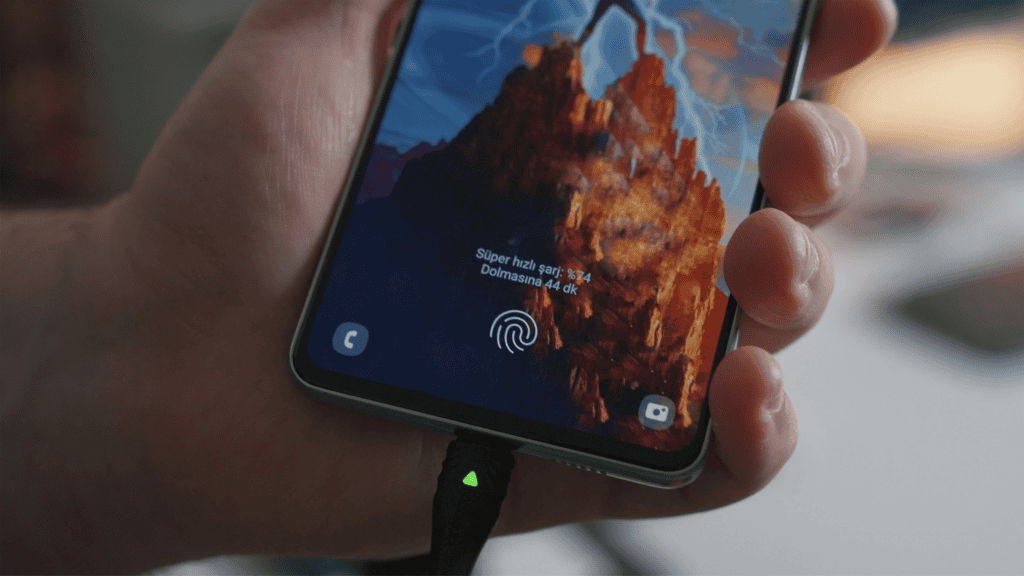 imagem mostra um celular na mão de uma pessoa enquanto aparelho está carregando