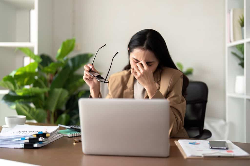 Mulher estressada sentada com a mão na cabeça na frente do notebook