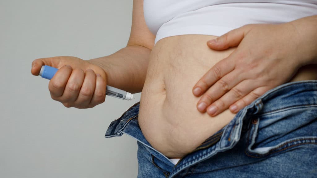 Mulher aplicando injeção de caneta emagrecedora na barriga