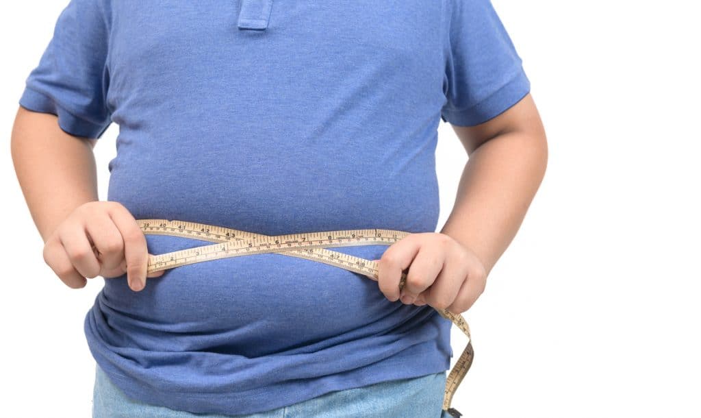 Pessoa obesa transpassando uma fita métrica por sua barriga
