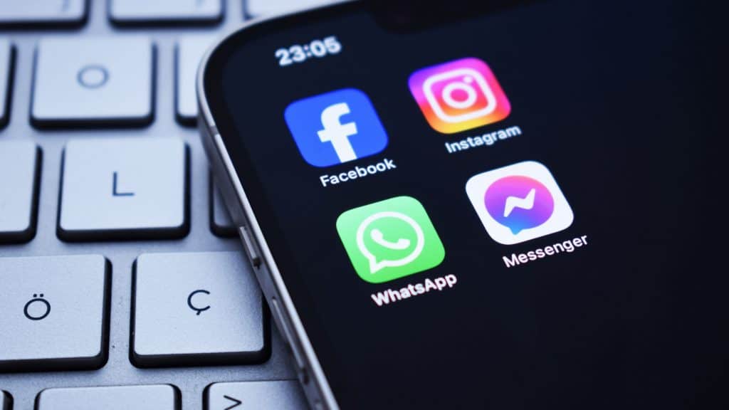 Ícones dos aplicativos do Facebook, Instagram, WhatsApp e Messenger, redes sociais da Meta, em tela inicial de um iPhone colocado sobre teclado de notebook